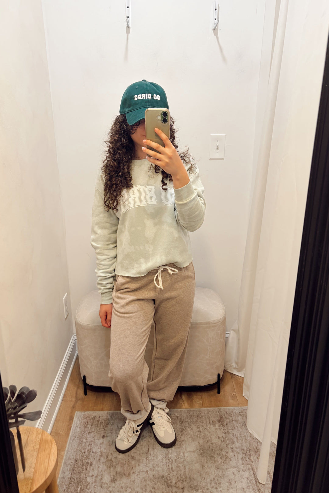 Stanton light sage green tie-dye sweatshirt with white lettering that says Go Birds, beige sweatpants, and a green baseball cap that says Go Birds.