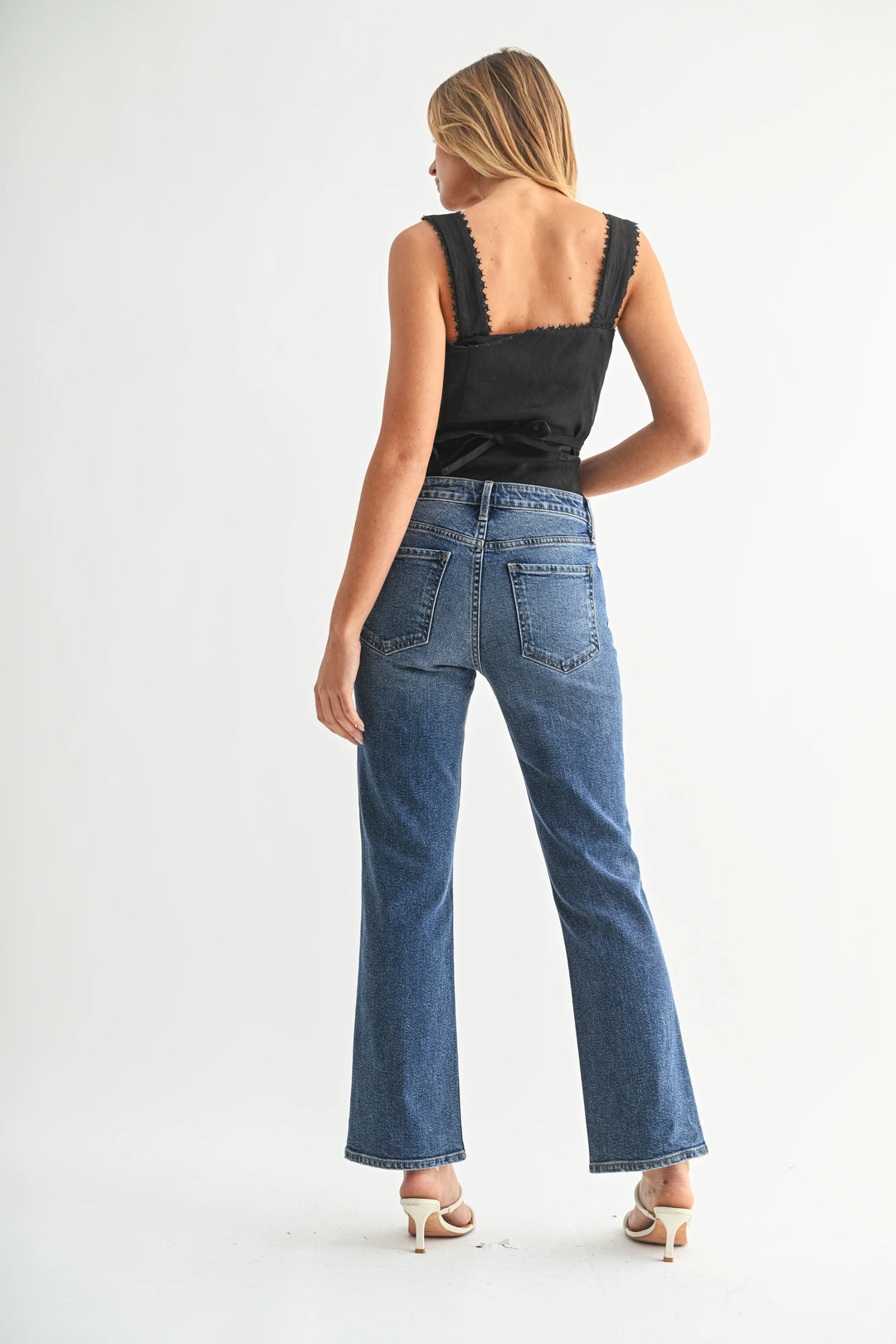 Woman wearing blue jeans and a black top on a white background