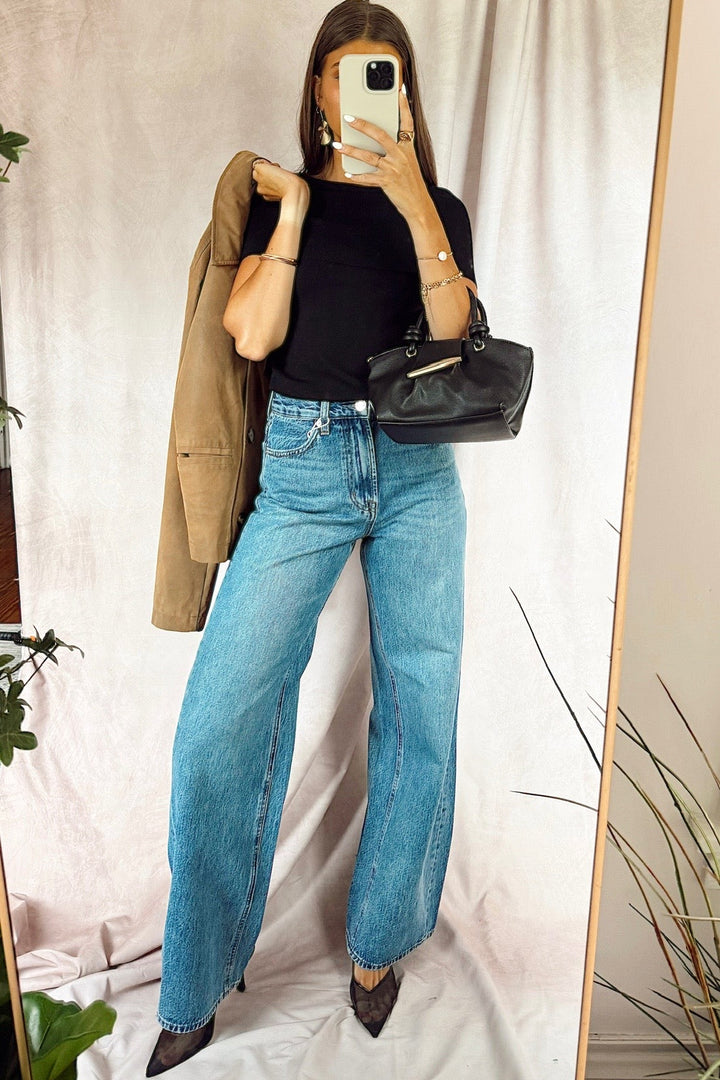 z supply The Head turner high rise wide leg denim jeans medium dark wash with a black off the shoulder top and a black handbag with a suede jacket over the shoulder from free people and black heels