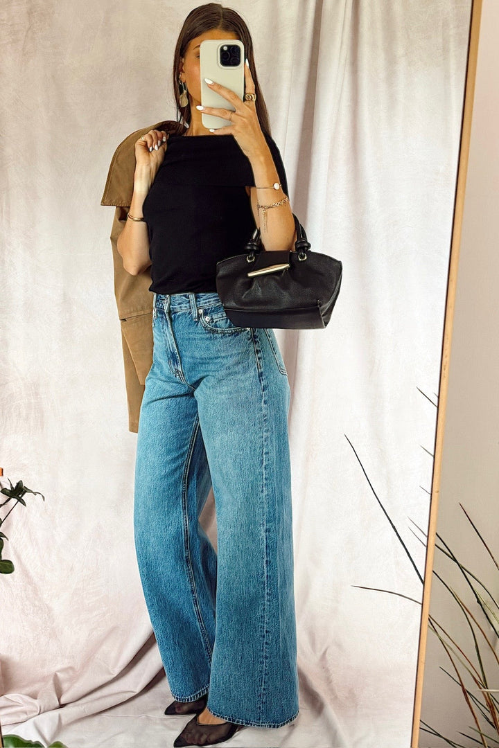 z supply The Head turner high rise wide leg denim jeans medium dark wash with a black off the shoulder top and a black handbag with a suede jacket over the shoulder from free people and black heels