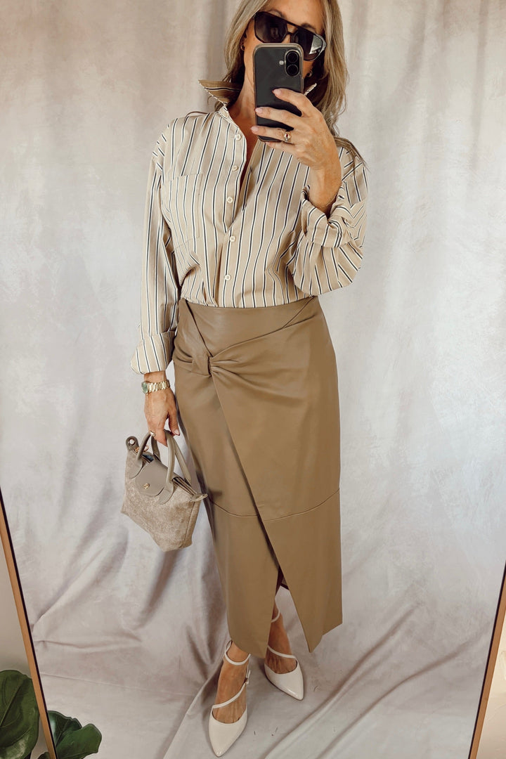 good American the easy poplin shirt long sleeve button front shirt dune tan with thin navy and white stripes paired with a tan faux leather midi skirt and white heels