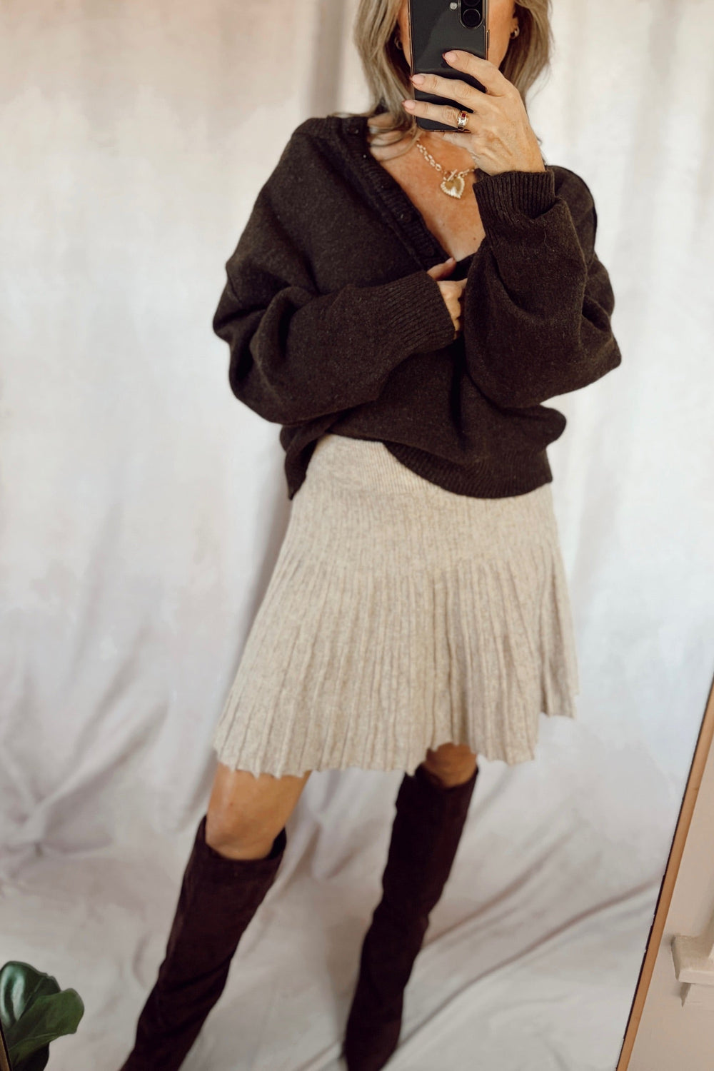 Stanton aubrey pullover sweater Henley exposed seam top dark brown with a beige mini skirt and tall brown suede boots