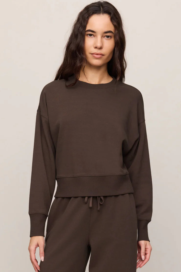 Woman wearing a brown sweatsuit outfit against a beige background