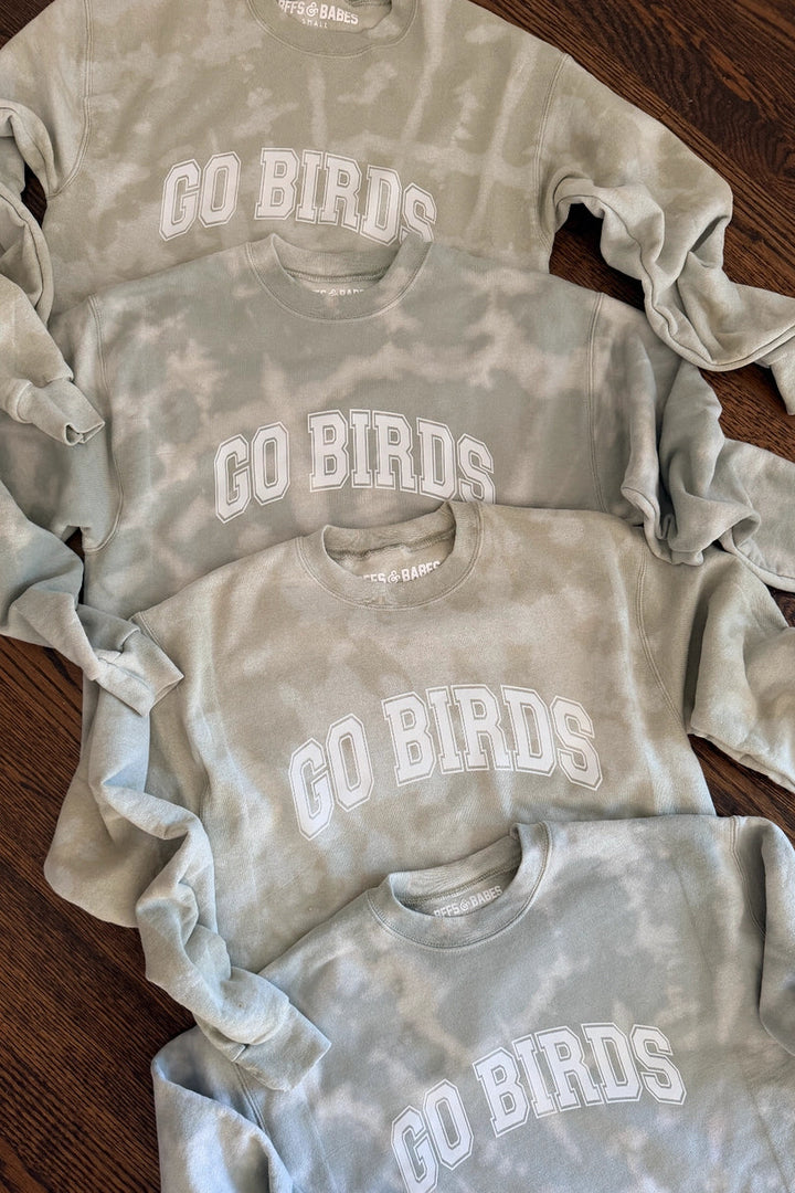 pullover sweatshirt in a light green, sage tie-dye color with "Go Birds" in White varsity lettering on the front