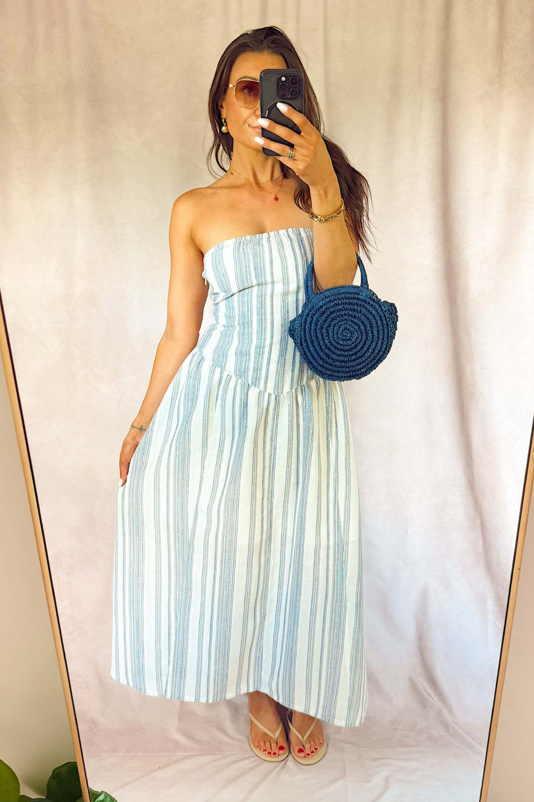 heartloom Ronan strapless midi ankle dress fit and flare eggshell white with navy blue stripes and a dark blue woven purse brass Sand strawberry pendant necklace