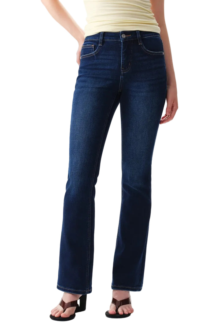A person wearing dark blue straight-leg  bootcut jeans with a light yellow top and brown sandals, shown from the waist down against a plain white studio background.
