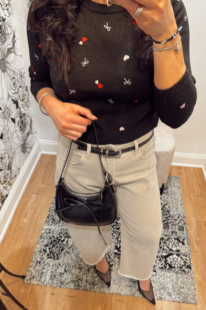 slim black faux leather belt styled with barrel jeans and a black sweater with embroidered hearts for valentine&