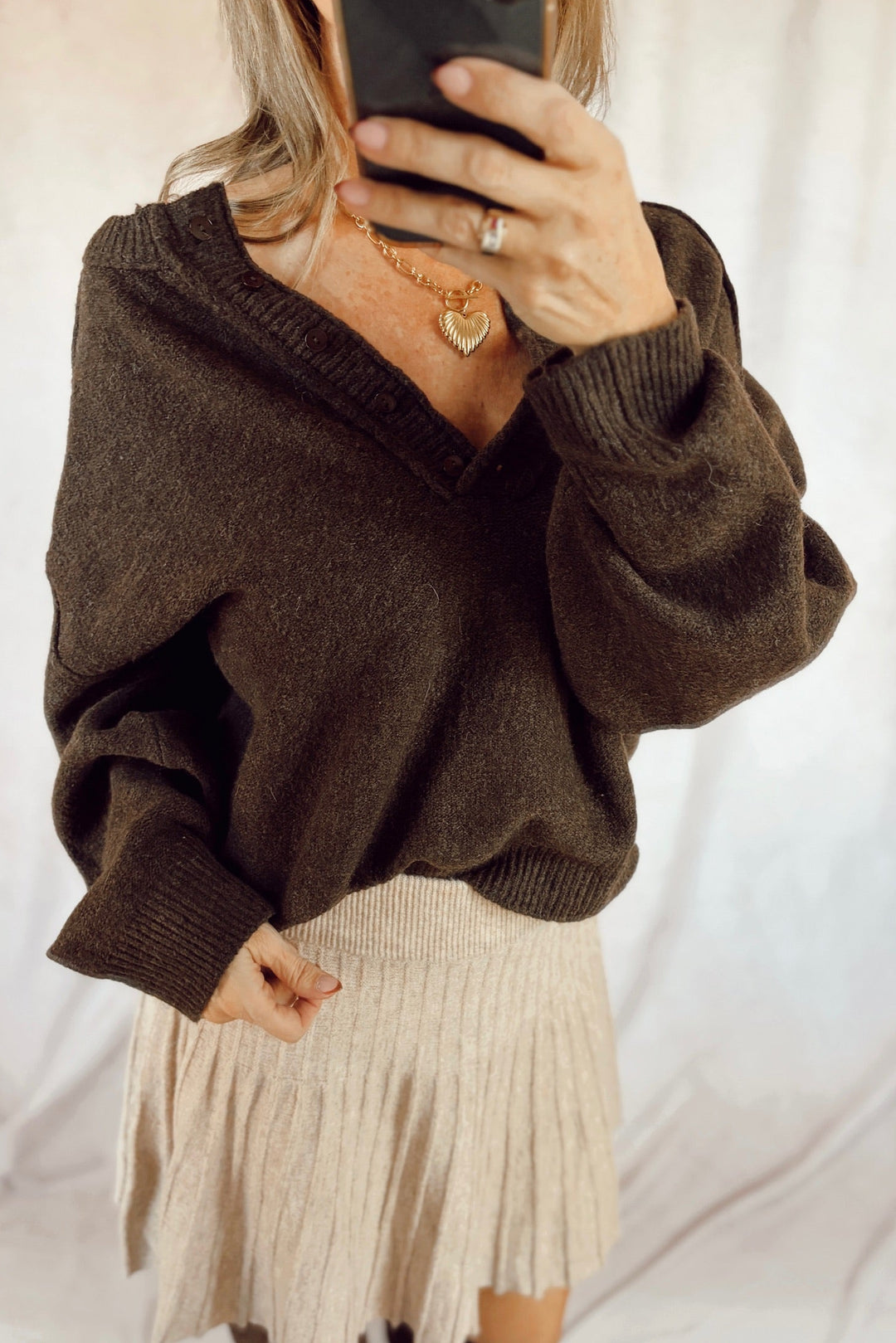 Stanton aubrey pullover sweater Henley exposed seam top dark brown with a beige mini skirt and tall brown suede boots
