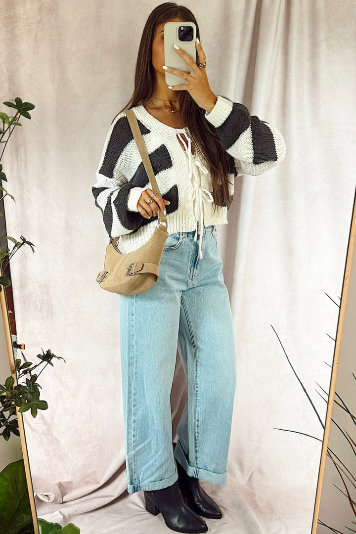 z supply the show off high rise bowed light wash denim with black booties and a striped loose knit cardigan with cream and charcoal stripes